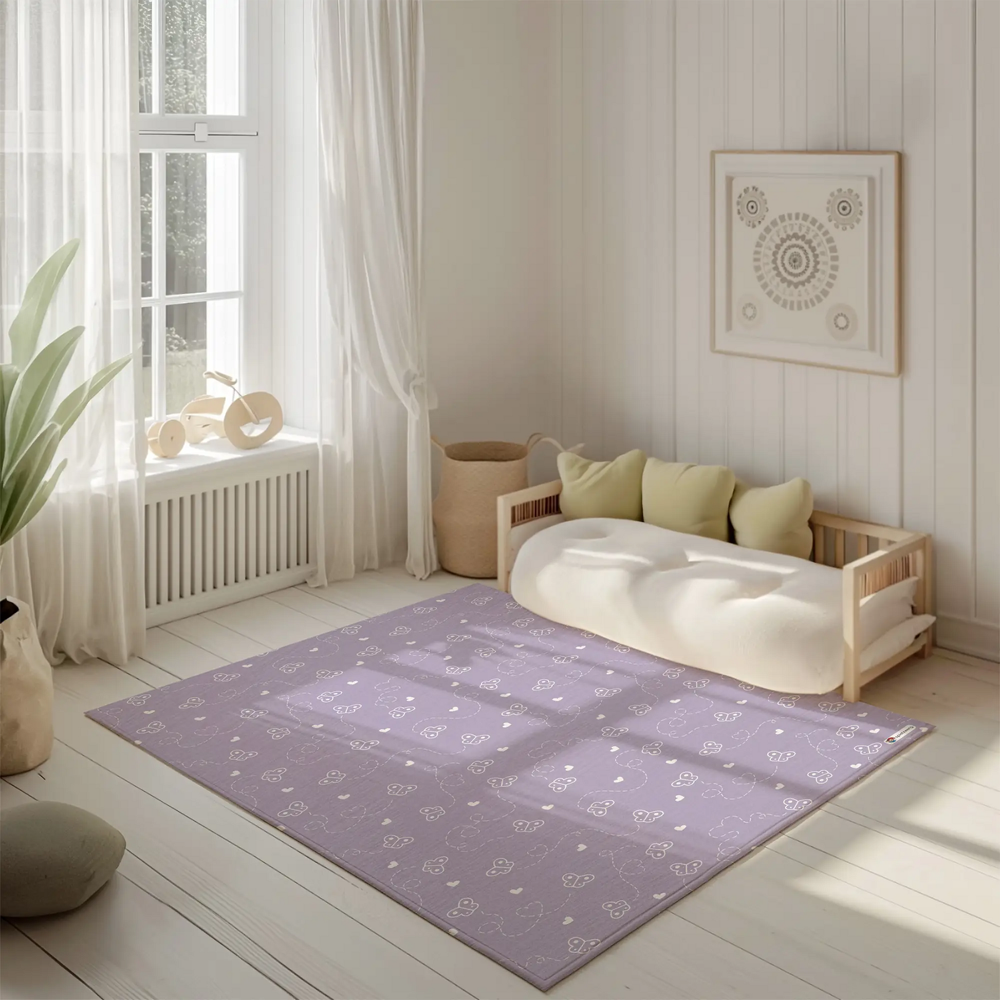 Kinderteppich "Chaotische Schmetterlinge" von spielzwerg. Ambientebild von einem hellen, freundlichen Kinderzimmer mit weißen Holzwänden und hellem Holzboden. In der Ecke steht ein niedriges Holzbett mit weißen Decken und hellgrünen Kissen. Davor liegt der Teppich. Links steht ein kleines Holzspielzeugrad am Fenster mit weißen Vorhängen. An der Wand hängt ein gerahmtes Bild mit einem dezenten, kreisförmigen Muster. RUG-00007-XL, RUG-00007-L.