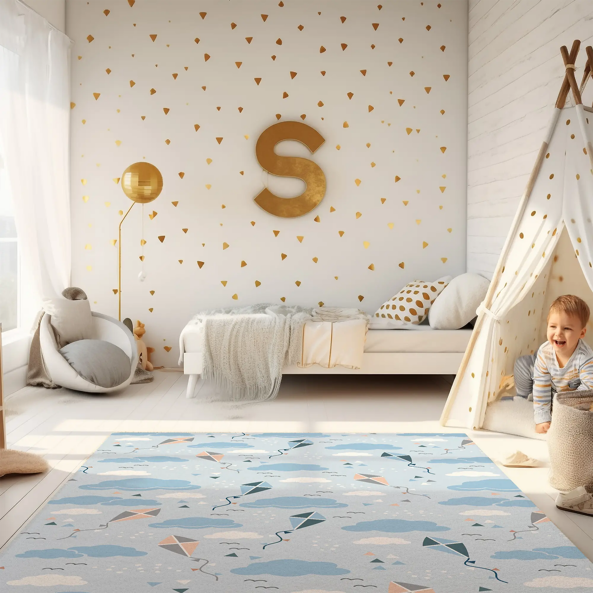 Kinderteppich "Drachensteigen" von spielzwerg. Ambientebild von einem hellen Kinderzimmer mit weißem Holzboden und weißen Wänden, dekoriert mit goldenen Dreiecken und einem großen goldenen Buchstaben 'S'. Links steht ein gemütlicher Sessel mit Kissen und Decke, daneben eine goldene Stehlampe. In der Mitte liegt der Teppich. Rechts sitzt ein lachender Junge in einem weißen Spielzelt mit goldenen Punkten. Im Hintergrund ein schlichtes Bett mit weißer Decke und goldenen Akzenten. RUG-00046-XL, RUG-00046-L.