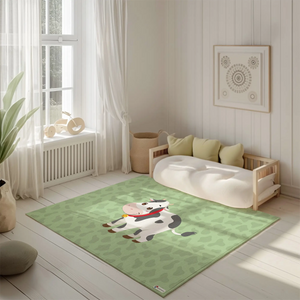 Kinderteppich "Klara Kuh" von spielzwerg. Ambientebild von einem hellen, freundlichen Kinderzimmer mit weißen Holzwänden und hellem Holzboden. In der Ecke steht ein niedriges Holzbett mit weißen Decken und hellgrünen Kissen. Davor liegt der Teppich. Links steht ein kleines Holzspielzeugrad am Fenster mit weißen Vorhängen. An der Wand hängt ein gerahmtes Bild mit einem dezenten, kreisförmigen Muster. RUG-00145-XL, RUG-00145-L.