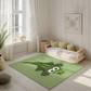 Kinderteppich "Kroko" von spielzwerg. Ambientebild von einem hellen, freundlichen Kinderzimmer mit weißen Holzwänden und hellem Holzboden. In der Ecke steht ein niedriges Holzbett mit weißen Decken und hellgrünen Kissen. Davor liegt der Teppich. Links steht ein kleines Holzspielzeugrad am Fenster mit weißen Vorhängen. An der Wand hängt ein gerahmtes Bild mit einem dezenten, kreisförmigen Muster. RUG-00202-XL, RUG-00202-L.