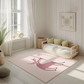 Kinderteppich "Frida" von spielzwerg. Ambientebild von einem hellen, freundlichen Kinderzimmer mit weißen Holzwänden und hellem Holzboden. In der Ecke steht ein niedriges Holzbett mit weißen Decken und hellgrünen Kissen. Davor liegt der Teppich. Links steht ein kleines Holzspielzeugrad am Fenster mit weißen Vorhängen. An der Wand hängt ein gerahmtes Bild mit einem dezenten, kreisförmigen Muster. RUG-00062-XL, RUG-00062-L.