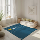 Kinderteppich „Süße Sterne“ von spielzwerg. Ambientebild von einem hellen, freundlichen Kinderzimmer mit weißen Holzwänden und hellem Holzboden. In der Ecke steht ein niedriges Holzbett mit weißen Decken und hellgrünen Kissen. Davor liegt der Teppich. Links steht ein kleines Holzspielzeugrad am Fenster mit weißen Vorhängen. An der Wand hängt ein gerahmtes Bild mit einem dezenten, kreisförmigen Muster. RUG-00158-XL, RUG-00158-L.