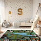 Spielteppich "Schwarzwald" von spielzwerg. Ambientebild von einem hellen Kinderzimmer mit weißem Holzboden und weißen Wänden, dekoriert mit goldenen Dreiecken und einem großen goldenen Buchstaben 'S'. Links steht ein gemütlicher Sessel mit Kissen und Decke, daneben eine goldene Stehlampe. In der Mitte liegt der Teppich. Rechts sitzt ein lachender Junge in einem weißen Spielzelt mit goldenen Punkten. Im Hintergrund ein schlichtes Bett mit weißer Decke und goldenen Akzenten. RUG-00197-XL, RUG-00197-L.