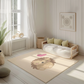 Kinderteppich "Schlummernder Igel" von spielzwerg. Ambientebild von einem hellen, freundlichen Kinderzimmer mit weißen Holzwänden und hellem Holzboden. In der Ecke steht ein niedriges Holzbett mit weißen Decken und hellgrünen Kissen. Davor liegt der Teppich. Links steht ein kleines Holzspielzeugrad am Fenster mit weißen Vorhängen. An der Wand hängt ein gerahmtes Bild mit einem dezenten, kreisförmigen Muster. RUG-00024-XL, RUG-00024-L.