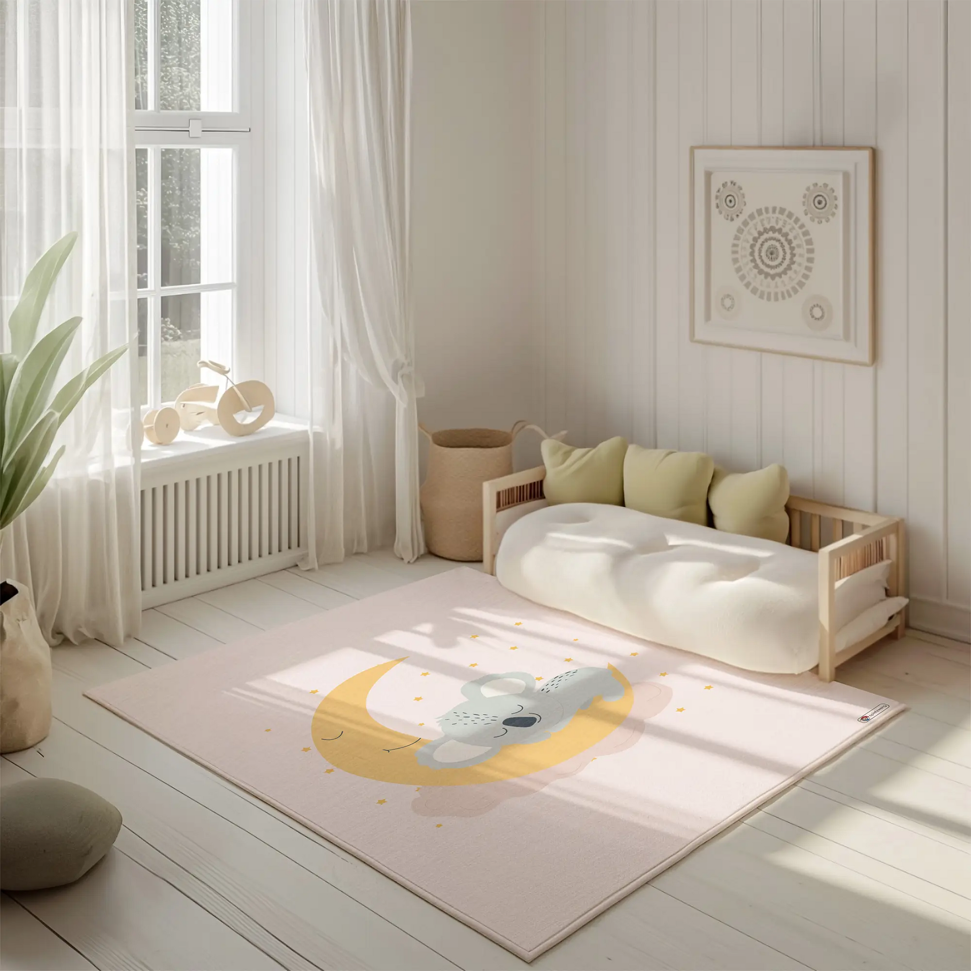 Kinderteppich "Maja Koala" von spielzwerg. Ambientebild von einem hellen, freundlichen Kinderzimmer mit weißen Holzwänden und hellem Holzboden. In der Ecke steht ein niedriges Holzbett mit weißen Decken und hellgrünen Kissen. Davor liegt der Teppich. Links steht ein kleines Holzspielzeugrad am Fenster mit weißen Vorhängen. An der Wand hängt ein gerahmtes Bild mit einem dezenten, kreisförmigen Muster. RUG-00095-XL, RUG-00095-L.