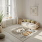Kinderteppich "Simba" von spielzwerg. Ambientebild von einem hellen, freundlichen Kinderzimmer mit weißen Holzwänden und hellem Holzboden. In der Ecke steht ein niedriges Holzbett mit weißen Decken und hellgrünen Kissen. Davor liegt der Teppich. Links steht ein kleines Holzspielzeugrad am Fenster mit weißen Vorhängen. An der Wand hängt ein gerahmtes Bild mit einem dezenten, kreisförmigen Muster. RUG-00096-XL, RUG-00096-L.