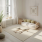 Kinderteppich "Emma" von spielzwerg. Ambientebild von einem hellen, freundlichen Kinderzimmer mit weißen Holzwänden und hellem Holzboden. In der Ecke steht ein niedriges Holzbett mit weißen Decken und hellgrünen Kissen. Davor liegt der Teppich. Links steht ein kleines Holzspielzeugrad am Fenster mit weißen Vorhängen. An der Wand hängt ein gerahmtes Bild mit einem dezenten, kreisförmigen Muster. RUG-00067-XL, RUG-00067-L.