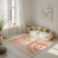 Kinderteppich "Regenbogen Boho Style" von spielzwerg. Ambientebild von einem hellen, freundlichen Kinderzimmer mit weißen Holzwänden und hellem Holzboden. In der Ecke steht ein niedriges Holzbett mit weißen Decken und hellgrünen Kissen. Davor liegt der Teppich. Links steht ein kleines Holzspielzeugrad am Fenster mit weißen Vorhängen. An der Wand hängt ein gerahmtes Bild mit einem dezenten, kreisförmigen Muster. RUG-00132-XL, RUG-00132-L.