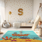 Kinderteppich "Piratenschiff" von spielzwerg. Ambientebild von einem hellen Kinderzimmer mit weißem Holzboden und weißen Wänden, dekoriert mit goldenen Dreiecken und einem großen goldenen Buchstaben 'S'. Links steht ein gemütlicher Sessel mit Kissen und Decke, daneben eine goldene Stehlampe. In der Mitte liegt der Teppich. Rechts sitzt ein lachender Junge in einem weißen Spielzelt mit goldenen Punkten. Im Hintergrund ein schlichtes Bett mit weißer Decke und goldenen Akzenten. RUG-00097-XL, RUG-00097-L.