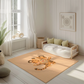 Kinderteppich "Tigerstark" von spielzwerg. Ambientebild von einem hellen, freundlichen Kinderzimmer mit weißen Holzwänden und hellem Holzboden. In der Ecke steht ein niedriges Holzbett mit weißen Decken und hellgrünen Kissen. Davor liegt der Teppich. Links steht ein kleines Holzspielzeugrad am Fenster mit weißen Vorhängen. An der Wand hängt ein gerahmtes Bild mit einem dezenten, kreisförmigen Muster. RUG-00013-XL, RUG-00013-L.